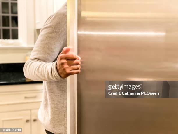african-american woman standing at open refrigerator - fridge door stock-fotos und bilder