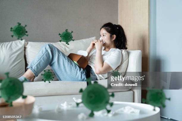 woman with the flu blowing her nose - infectious disease fotografías e imágenes de stock
