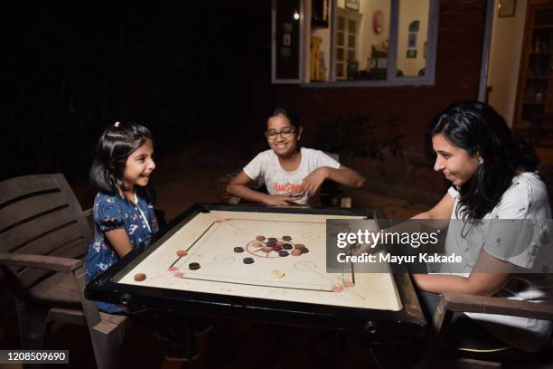 mother with two daughters playing board game - family game night stock pictures, royalty-free photos & images