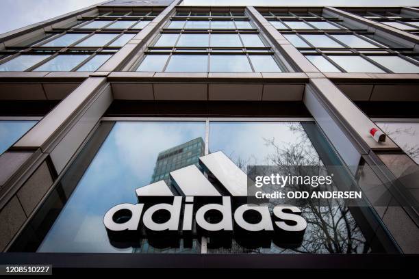 The logo of German sporting goods company Adidas is pictured at one of the company's outlets in Berlin on March 29, 2020. - Major retailers in...
