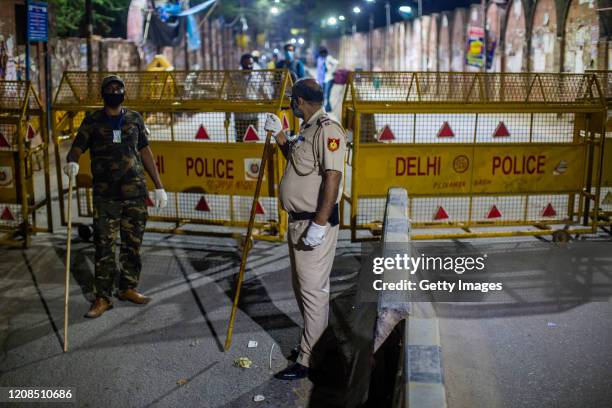 Indian policemen stand guard on a deserted road to enforces a lockdown during night, as nationwide lockdown continues over the highly contagious...