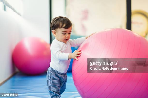 baby junge spielen mit einem fitness-ball - gymnastiek stock-fotos und bilder