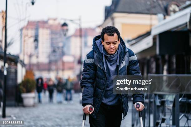 man using walking canes for walking downtown injury - crutch stock pictures, royalty-free photos & images