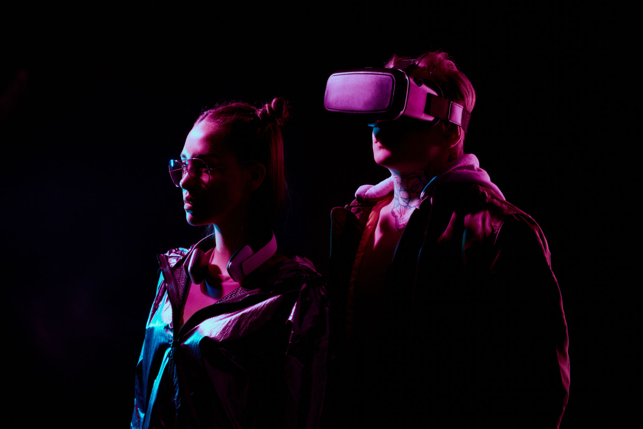 Side view of serious young couple using virtual reality simulator in darkness Side view of serious young couple using virtual reality simulator in darkness