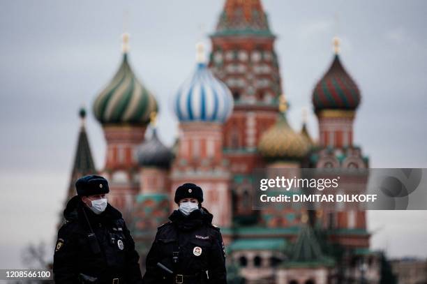 Russian police officers patrol on March 30, 2020 on the deserted Red square in front of Saint Basil's Cathedral in Moscow as the city and its...