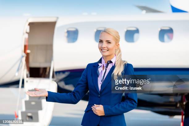 beautiful air stewardess in front of private airplane - air hostess stock pictures, royalty-free photos & images