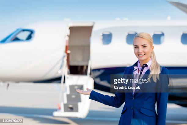 beautiful air stewardess in front of private airplane - airhostess stock pictures, royalty-free photos & images