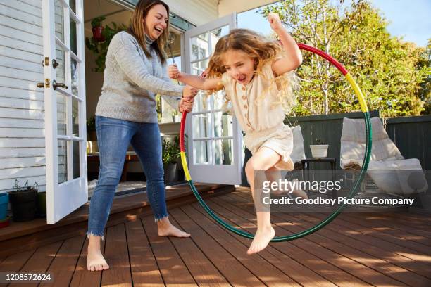 mom and cute little daughter playing with a hulahoop outside - jogar ao arco imagens e fotografias de stock