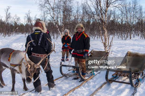 Sami people in the snow with a traditional Sami sled at the Sami village of Ravttas near Kiruna in Swedish Lapland, northern Sweden.