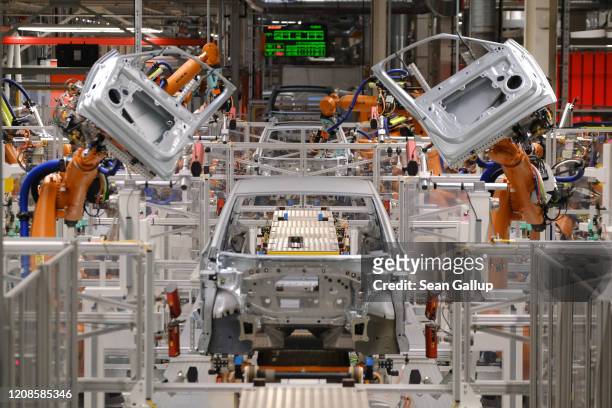 Kuka industrial robots prepare to attach doors to the body of an ID.3 electric car at the Volkswagen factory on February 25, 2020 in Zwickau,...