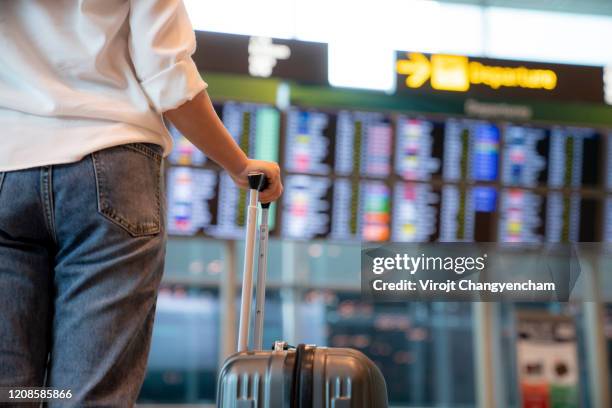 female traveller standing in front of flight display schedule in the international airport - flight stock pictures, royalty-free photos & images