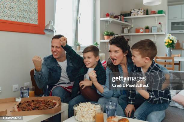 family watching sports on television and cheering - american football family stock pictures, royalty-free photos & images