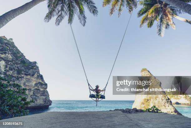 woman on the swing over beautiful beach in bali - coconut beach woman stock pictures, royalty-free photos & images