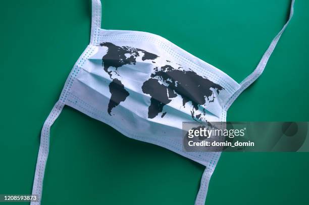 White face mask with a map of the world is lying on a green background