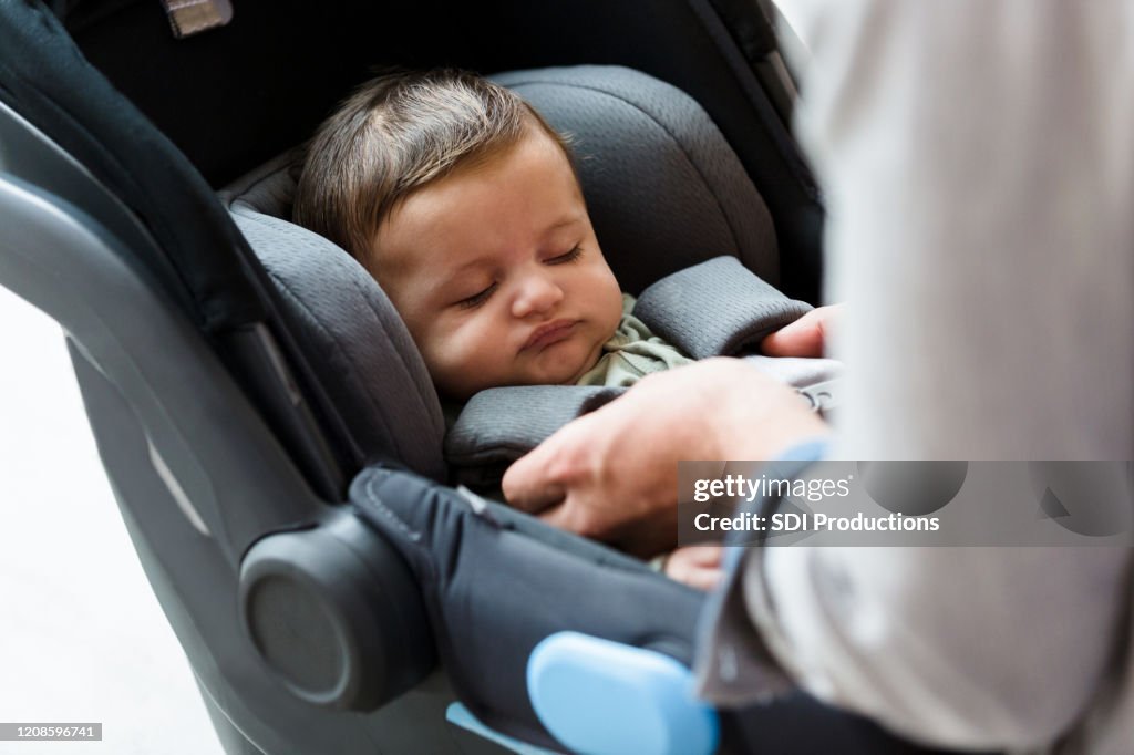 お父さんは車の座席に赤ちゃんをストラップ
