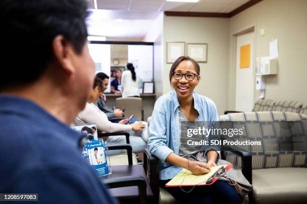 de medio volwassen vrouw en onherkenbare mensenbabbel in wachtkamer - patients in doctors waiting room stockfoto's en -beelden