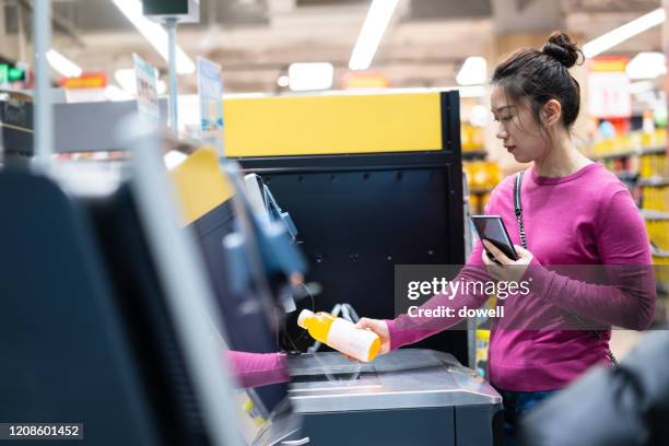 female checkout by contactless payment using mobile phone - supermarket register stockfoto's en -beelden