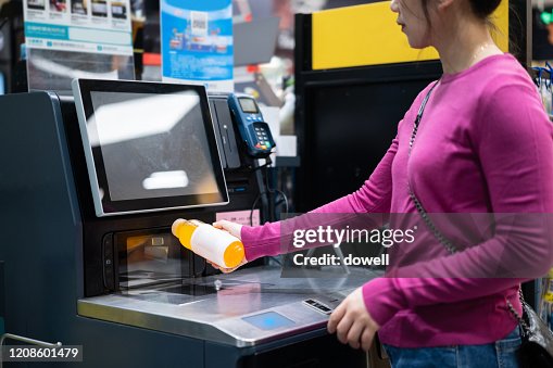 Female checkout by automatic payment machine in supermarket Female checkout by automatic payment machine in supermarket