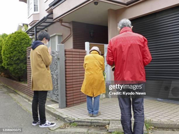People pray on March 30 in front of the home of veteran Japanese comedian Ken Shimura, who died of pneumonia caused by the novel coronavirus the...