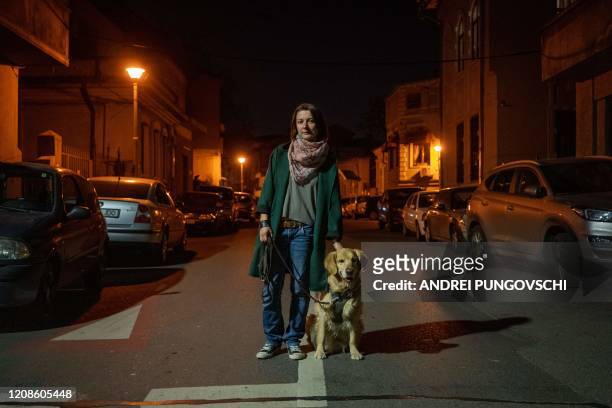Ioana Epure, 31 years old, poses for a portrait during one of the daily walks outside with her 6-year-old dog Asimov on March 28, 2020 in Bucharest....