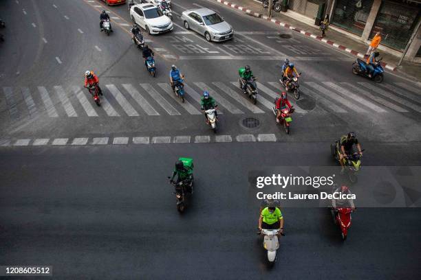 Motorbike food delivery drivers on Sukhumvit Road on March 30, 2020 in Bangkok, Thailand. Due to the spread of Covid-19, Bangkok called for an...