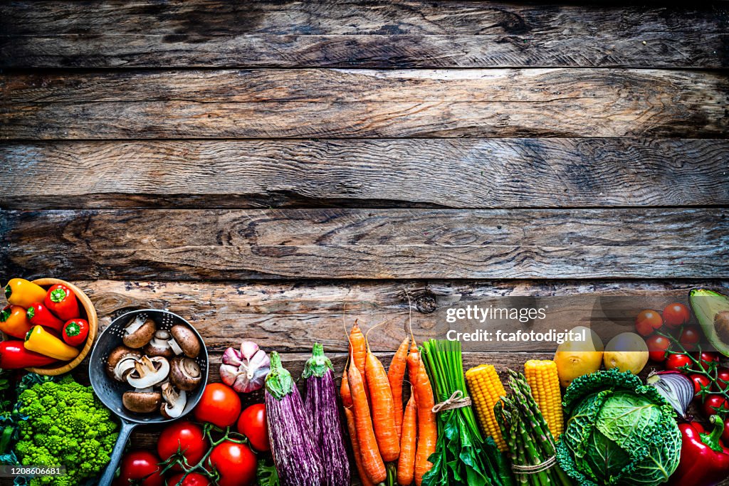 Friska färska grönsaker gränsen skott uppifrån på rustika träbord. Kopiera blanksteg