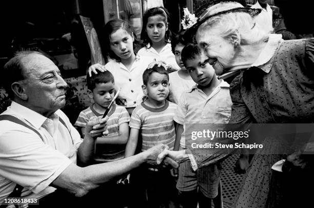 Watched by a group of children, American actors Buster Keaton and Nell Harrison shake hands during the filming of their movie, 'Film' , New York, New...