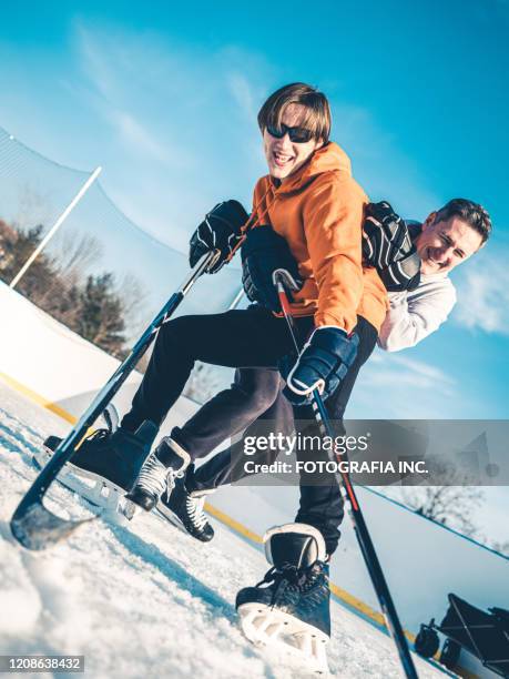 father and son playing hockey outdoors - checking ice hockey stock pictures, royalty-free photos & images