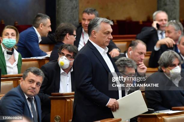 Hungarian Prime Minister Viktor Orban walks near other representatives during a vote about the government's bill on the protection against the new...