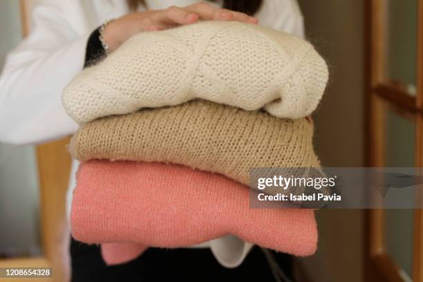 woman holding stack of warm sweaters - cardigan sweater stock pictures, royalty-free photos & images