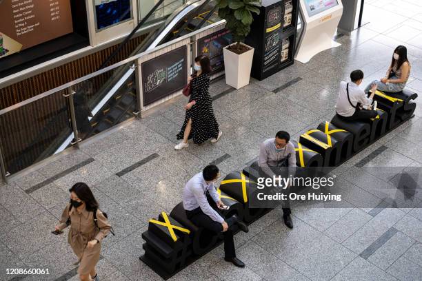 People sit along benches in The Central mall according to safe distancing markers on March 30, 2020 in Singapore. The Singapore government has...