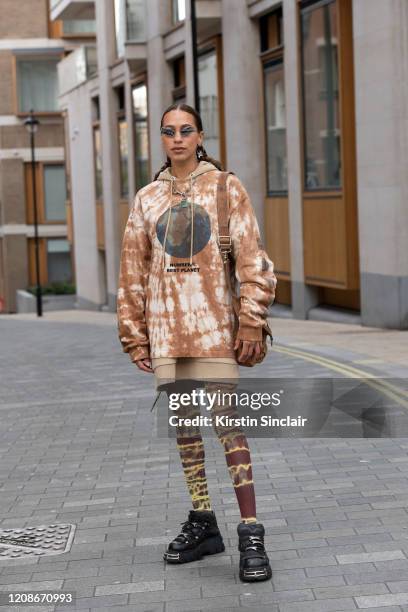 Musician Maeve wears M.Y.O.B hooded sweatshirt and bag, Celia Calderón Asensio tights, New Rock shoes and 4NN4 earrings during London Fashion Week...