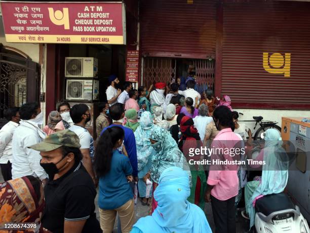 People crowd outside a Punjab National Bank branch to withdraw money on day 6 of the 21-day nationwide lockdown imposed by PM Narendra Modi to check...