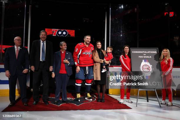 Alex Ovechkin of the Washington Capitals acknowledges the crowd with his son, Sergei Ovechkin, wife Nastya Shubskaya as he is honored for scoring 700...