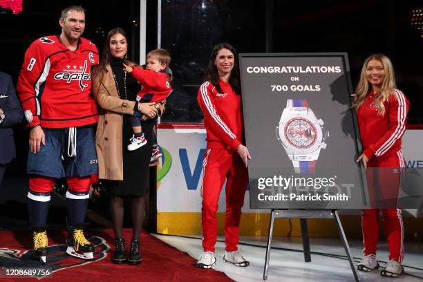 Alex Ovechkin of the Washington Capitals acknowledges the crowd with his son, Sergei Ovechkin, wife Nastya Shubskaya as he is honored for scoring 700...