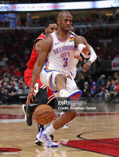 Chris Paul of the Oklahoma City Thunder dribbles between his legs as he passes Shaquille Harrison of the Chicago Bulls at the United Center on...