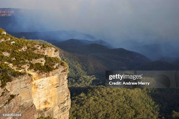 sandstone cliff, escarpment with valley of trees and distant bushfire smoke, blue mountains, australia - three sisters blue mountains stock pictures, royalty-free photos & images