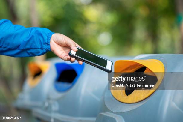 close-up of woman hand throwing smartphone in litter bin outdoors. - electrical equipment stock pictures, royalty-free photos & images
