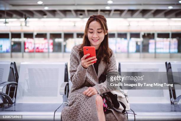 young lady using smartphone joyfully on train platform - railroad station platform stockfoto's en -beelden
