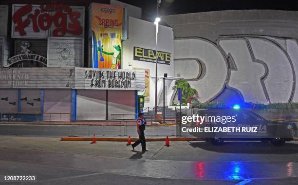 Police officer and his car are seen outside closed bars in Cancun, Quintana Roo state, Mexico, on March 28, 2020. - A significant drop in the number...