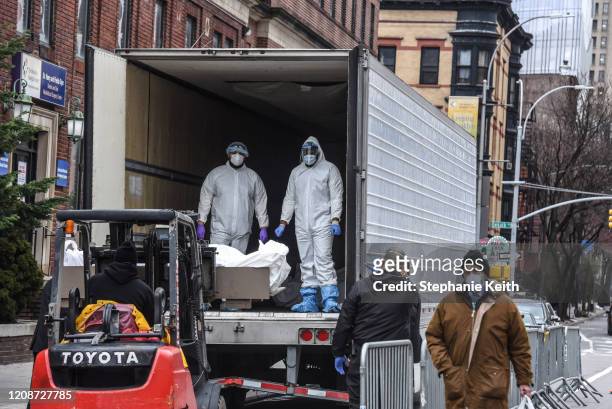 Medical workers wearing personal protective gear remove a body from a refrigerator truck outside of the Brooklyn Hospital on March 31, 2020 in New...