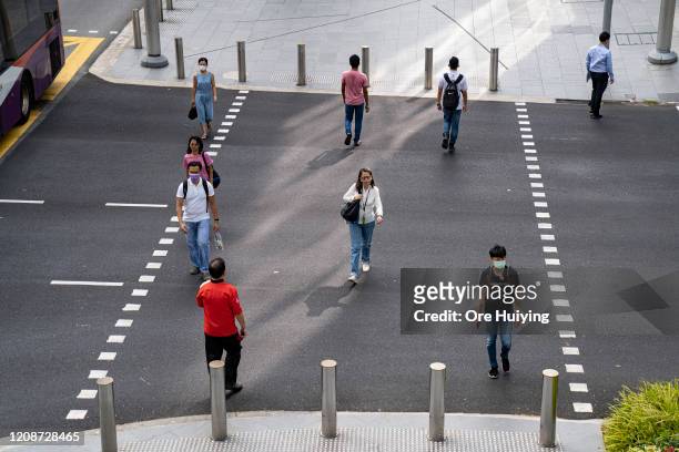 People keep their distance apart from each other while crossing a traffic junction on Orchard Road on March 31, 2020 in Singapore. The Singapore...
