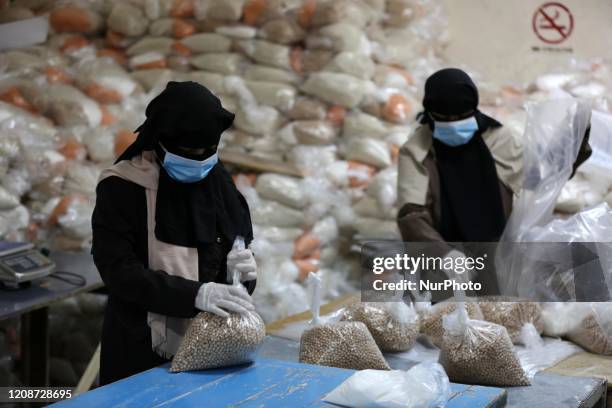 Palestinian employees at the United Nations Relief and Works Agency for Palestinian Refugees wearing protective masks and gloves, prepare food aid...