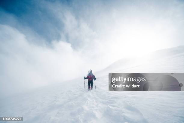 elderly alpine mountain climber is climbing to the peak of high altitude mountain in winter - blizzard stock pictures, royalty-free photos & images