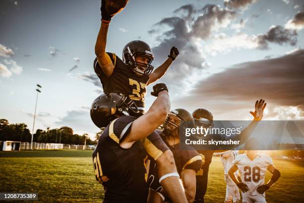 team of american football players celebrating victory at sunset. - american football player celebrating stock pictures, royalty-free photos & images