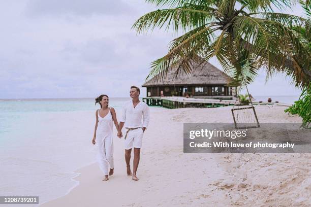 lovers walking on the beach in maldives, young adult couple enjoying vacation on the beach, ocean, romance, summer, loving and happy - private beach stock pictures, royalty-free photos & images