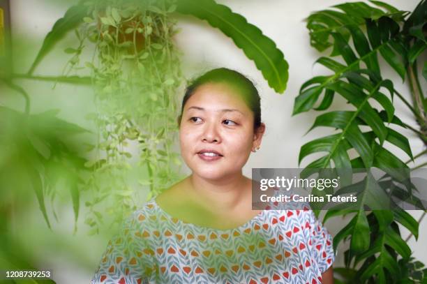 portrait of a woman with her houseplants - ミッドアダルト ストックフォトと画像