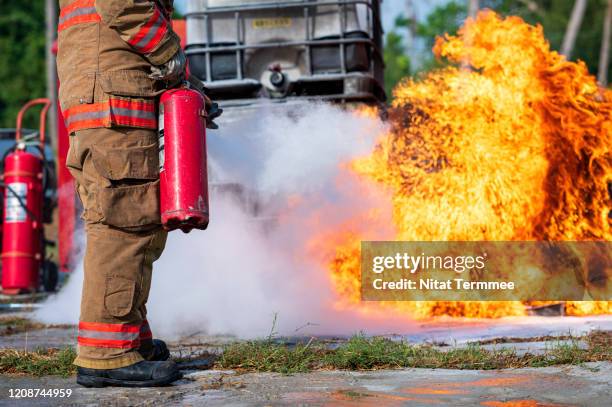 close-up of firefighter instructor showing how to use a fire extinguisher on a training fire. - emergency services australia imagens e fotografias de stock