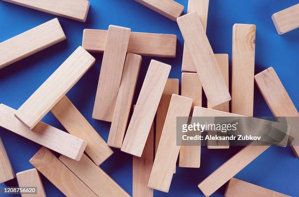 a pile of scattered wooden blocks on a blue background. construction game. the broken tower. - jenga stockfoto's en -beelden