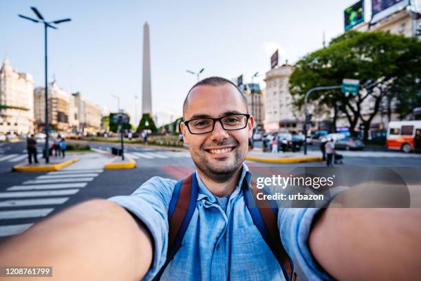 mens die selfie met obelisco van buenos aires maakt - obelisco de buenos aires stockfoto's en -beelden